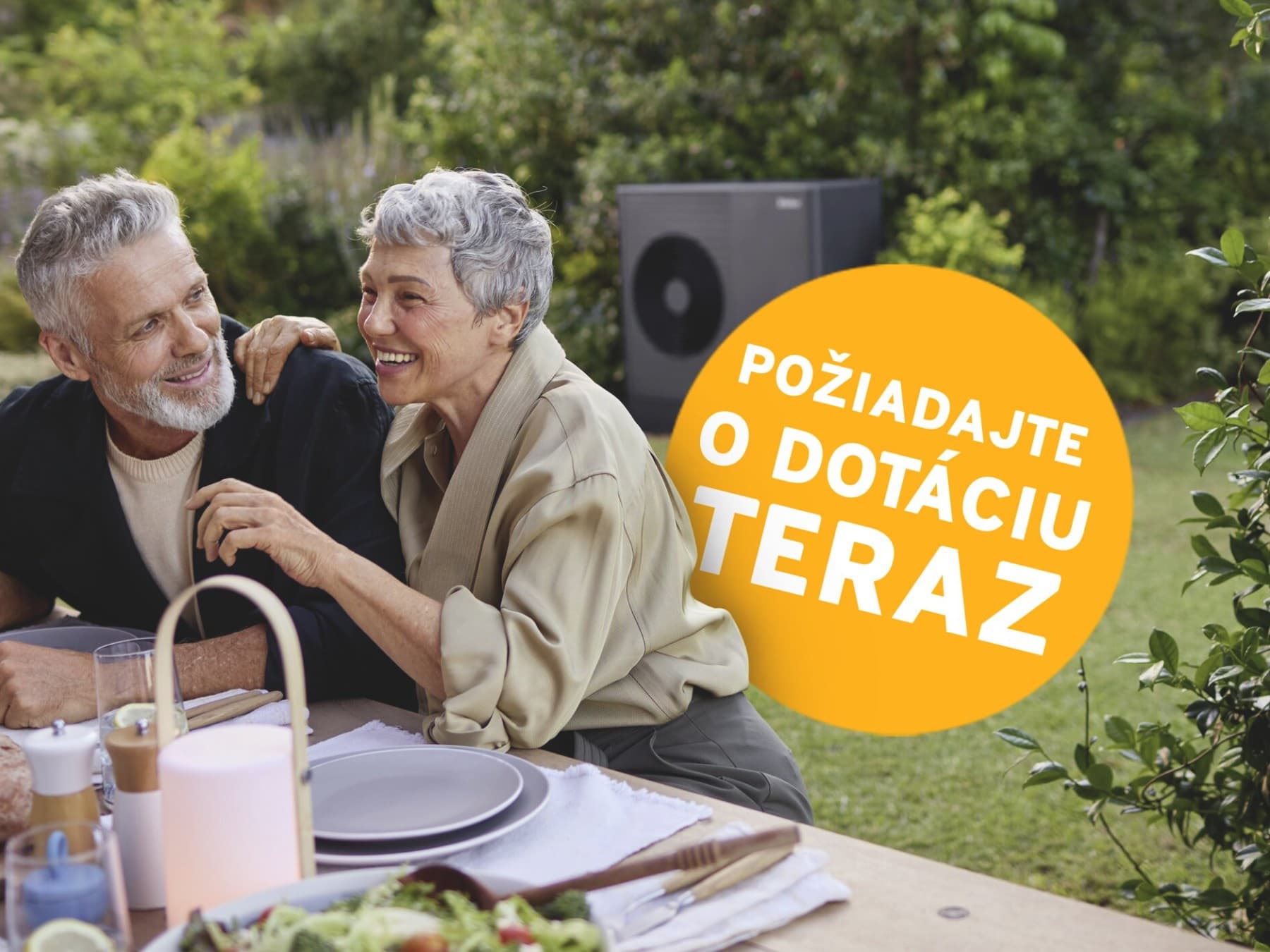 Pár sedí na terase pri jedle, v pozadí je tepelné čerpadlo